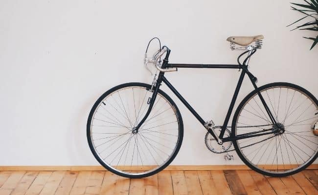 Bicicleta apoyada directamente en una pared de casa.